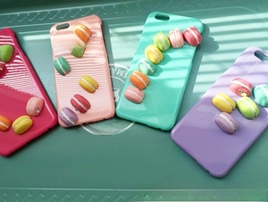 Detailed close-up of macaron resin charms on colorful smartphone cases in a display tray
