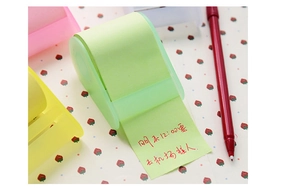 Close-up of light green transparent sticky note dispenser with adhesive tape roll