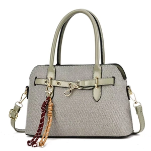 Détail du sac à main en toile grise avec bordure en cuir vert et fermoirs dorés
