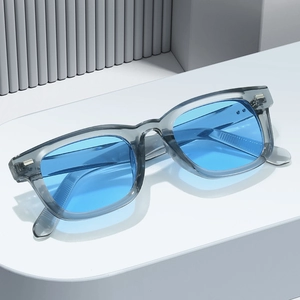 Moderne quadratische Sonnenbrille in transparentem Grau mit blauen Gläsern und Nieten