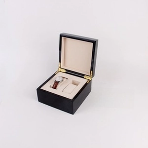 Detail of high-gloss black lacquer watch box with beige velvet lining and golden hinges