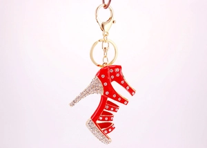 Close-up of golden high heel keychain with red enamel and sparkling rhinestones