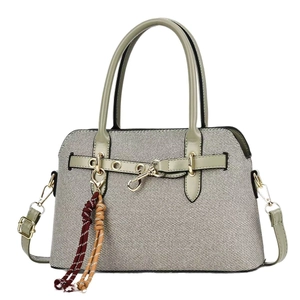 Sac à main beige tissé élégant avec bandoulière en cuir vert et pompon coloré décoratif