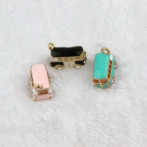 Three enamel bus pendants in black, pink, and teal with gold borders and rhinestones