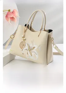 Detailaufnahme der eleganten Lilienstickerei und der perlgoldenen Hardware der Handtasche