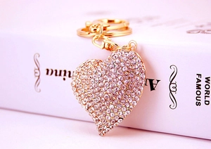 Detailed close-up of a sparkling heart-shaped keychain with gold metal and white rhinestones