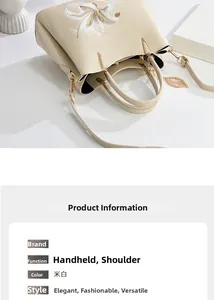 Detail der cremeweißen Handtasche mit Blumenstickerei und goldenem Blattanhänger