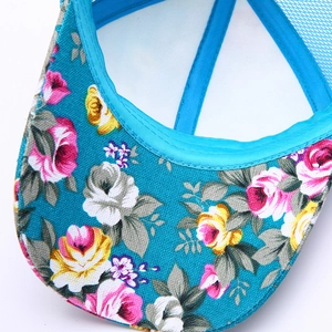 Detailed close-up of blue floral baseball cap featuring pink rose prints and mesh side