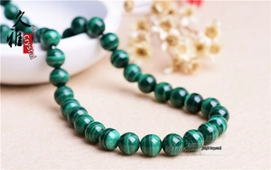 Macro shot of polished malachite round beads showing natural deep green banding and textures