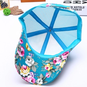 Detail view of the floral print brim and breathable mesh interior of a blue trucker hat