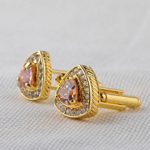 Close-up of men's gold triangle cufflinks with orange crystals and diamond halo
