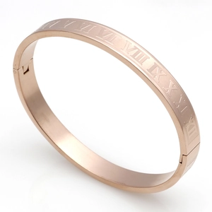 Detail of rose gold bangle featuring engraved Roman numerals and side hinge closure