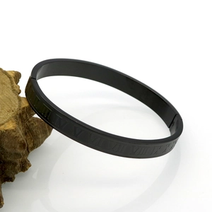 Detail of matte black stainless steel bangle with engraved Roman numerals on a wooden stand