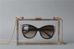 Macro view of transparent acrylic evening clutch with gold metal frame and snake chain