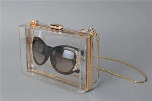 Detail of clear acrylic evening clutch bag with gold frame and detachable chain strap