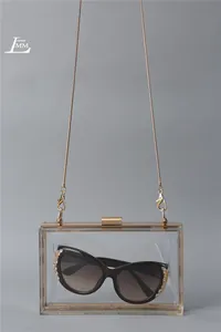 Close-up of clear acrylic box clutch featuring a gold chain and elegant snap closure