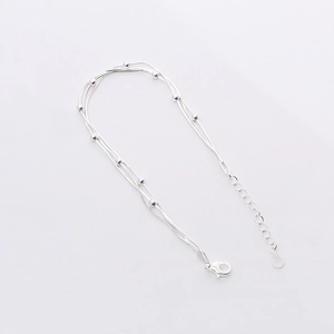 Macro detail of multi-layer S925 silver beaded bracelet with lobster clasp and chain