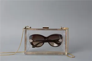 Detailed close-up of transparent acrylic box clutch with gold metal chain and snap closure