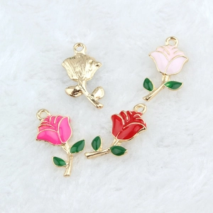 Detailed view of rose flower alloy pendants in red and pink colors on white plush fabric