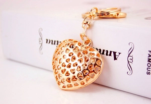 Detailed view of a gold hollow heart keychain pendant on a white book surface