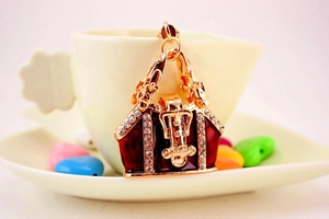 Detailed close-up of a golden handbag keychain with red enamel and sparkling crystals