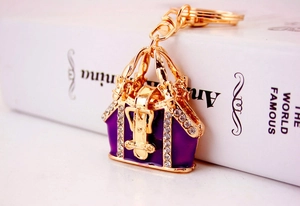 Detailed close-up of a golden keychain with a purple handbag pendant and clear crystals