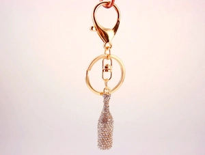 Detail of a sparkling crystal beer bottle keychain with gold lobster clasp and rhinestones