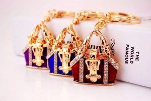 Close-up of enamel handbag keychains in purple, blue, and red with rhinestone details