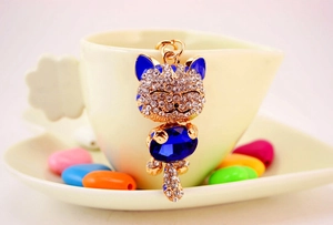 Detailed close-up of a sparkling rhinestone lucky cat keychain with deep blue gemstone