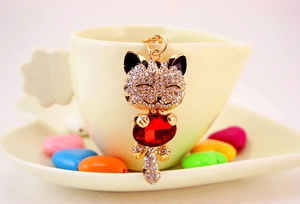 Macro detail of gold lucky cat keychain with white rhinestones and a red gem