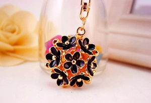 Macro detail of 3D black enamel flower ball keychain with gold trim and lobster clasp