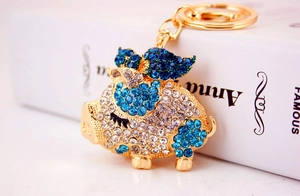 Close-up of a golden flying pig keychain with sparkling blue and clear rhinestones