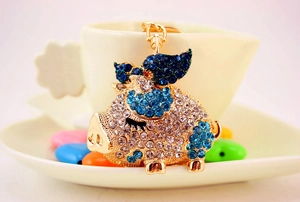 Macro detail of golden flying pig keychain with blue and white sparkling crystals