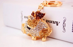 Detailed macro of a golden pig keychain with crystal rhinestones on a book background