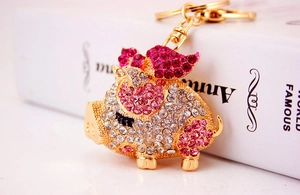Macro shot of a golden flying pig keychain with sparkling pink and white rhinestones