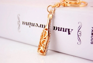 Macro shot of gold-plated wine bottle keychain with sparkling crystals and hollow design