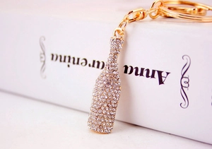 Macro shot of gold wine bottle keychain with crystal rhinestones on a white book