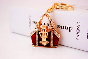 Detail of red enamel handbag keychain with rhinestones against a blurred book background