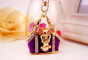 Detail of purple enamel handbag keychain with gold metal accents and sparkling rhinestones