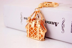 Close-up of golden handbag keychain with clover cutout details on a white book