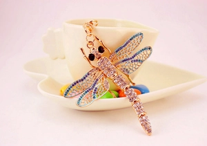 Detailed macro view of dragonfly keychain with blue purple crystals and gold metal