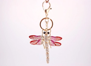 Macro detail of gold dragonfly keychain with pink enamel wings and crystals