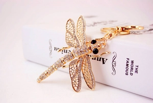 Close-up of golden metal dragonfly keychain with clear crystals and black rhinestone eyes