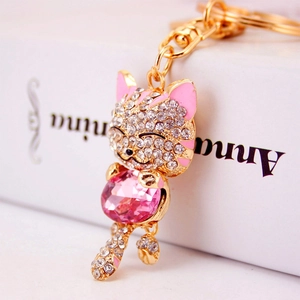 Golden lucky cat keychain with pink crystal and white rhinestones on white background