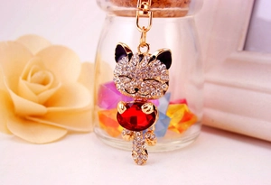 Macro shot of gold cat keychain with white rhinestones and a large red crystal