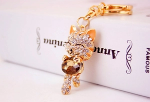 Detail of a lucky cat keychain with white rhinestones and a large amber gemstone