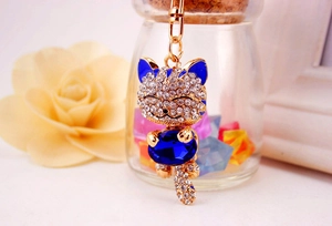 Close-up of lucky cat keychain with blue gemstone and sparkling rhinestones