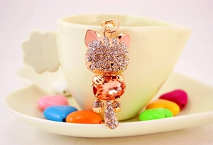 Detail of rose gold lucky cat keychain with orange gemstone and sparkling rhinestones