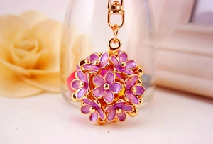 Detailed macro view of purple flower keychain with gold accents and enamel petals