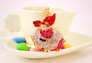 Close-up of a sparkling gold flying pig keychain with red and clear rhinestones